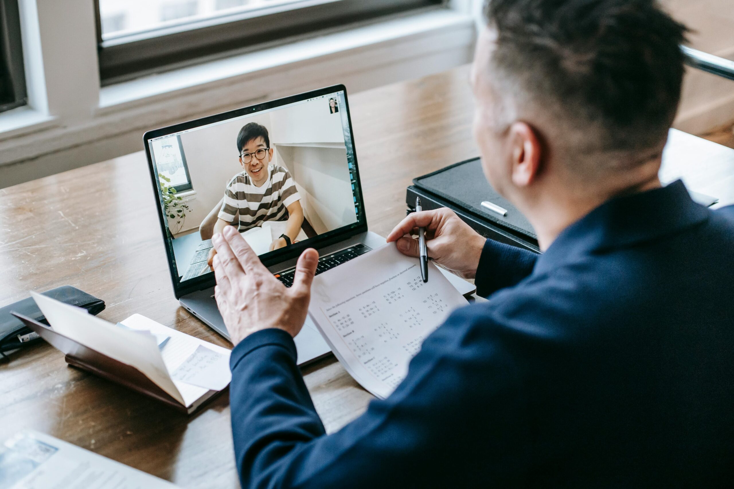 A middle-aged man wearing a blue button-up shirt on a video call, having a legal document drafted for him.