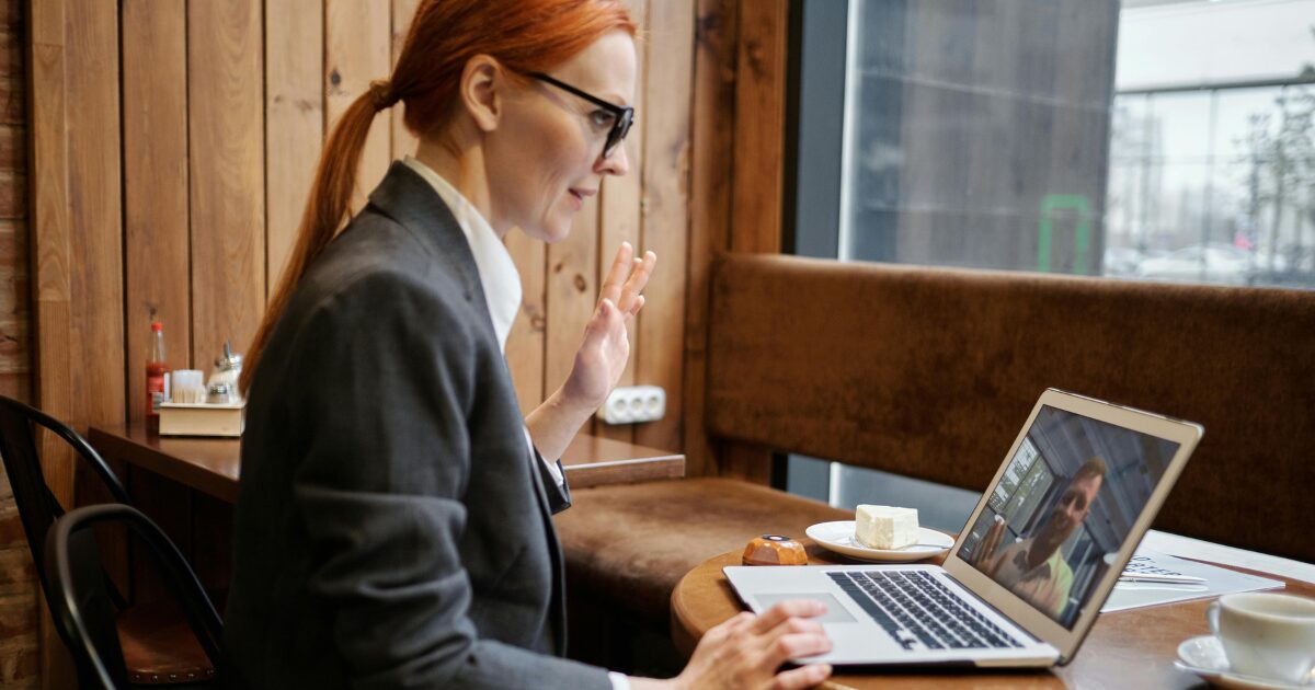 Caucasian woman sitting at a desk, taking an affirmation with her hand up during a virtual notary appointment.